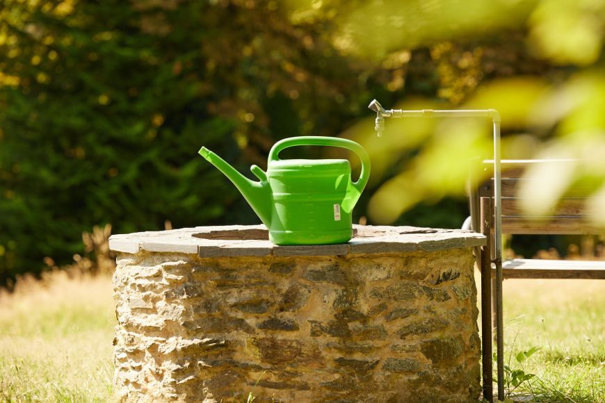 Steinerner Brunnen mit Gießkanne auf dem Friedhof