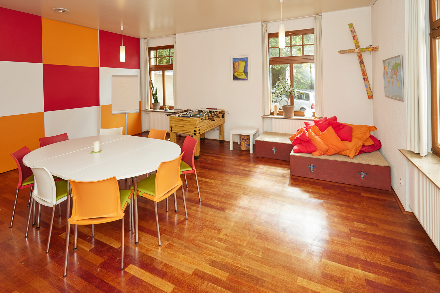 Jugendraum im Gemeindehaus mit rundem Tisch und Stühlen, Tischkicker und Chill-Ecke